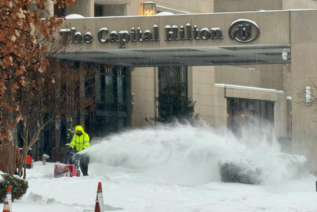 A worker uses a snow blower near the entrance of a hotel as snow falls in Washington, DC, on January 25, 2026. A massive winter storm on January 24 dumped snow and freezing rain from New Mexico to North Carolina as it swept across the United States towards the northeast, threatening tens of millions of Americans with blackouts, transportation chaos and bone-chilling cold. After battering the country's southwest and central areas, the storm system began to hit the heavily populated mid-Atlantic and northeastern states as a frigid air mass settled in across the nation. (Photo by Daniel SLIM / AFP)