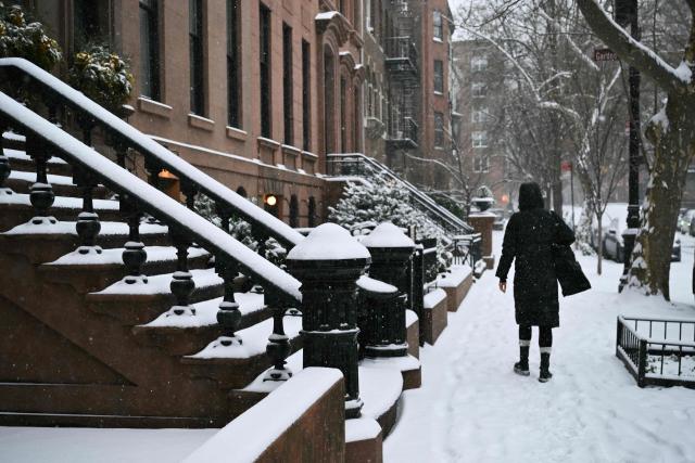A person walks along a sidewalk of a residential street as snow falls in the Brooklyn borough of New York City on January 25, 2026. A massive winter storm on January 24 dumped snow and freezing rain from New Mexico to North Carolina as it swept across the United States towards the northeast, threatening tens of millions of Americans with blackouts, transportation chaos and bone-chilling cold. After battering the country's southwest and central areas, the storm system began to hit the heavily populated mid-Atlantic and northeastern states as a frigid air mass settled in across the nation. (Photo by ANGELA WEISS / AFP)