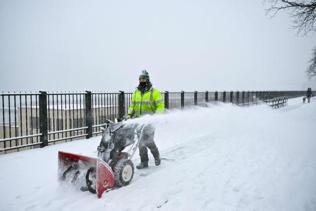 A worker clears snow from the Brooklyn Heights Promenade in New York City on January 25, 2026. A massive winter storm on January 24 dumped snow and freezing rain from New Mexico to North Carolina as it swept across the United States towards the northeast, threatening tens of millions of Americans with blackouts, transportation chaos and bone-chilling cold. After battering the country's southwest and central areas, the storm system began to hit the heavily populated mid-Atlantic and northeastern states as a frigid air mass settled in across the nation. (Photo by ANGELA WEISS / AFP)