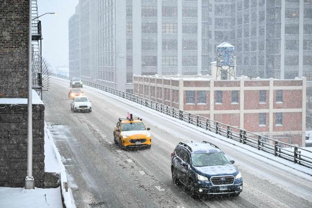 Vehicles drive as snow falls in the Brooklyn borough of New York City on January 25, 2026. A massive winter storm on January 24 dumped snow and freezing rain from New Mexico to North Carolina as it swept across the United States towards the northeast, threatening tens of millions of Americans with blackouts, transportation chaos and bone-chilling cold. After battering the country's southwest and central areas, the storm system began to hit the heavily populated mid-Atlantic and northeastern states as a frigid air mass settled in across the nation. (Photo by ANGELA WEISS / AFP)