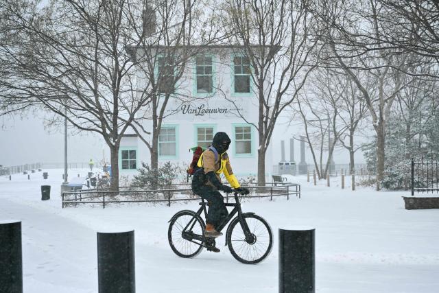 A man rides his bike as snow falls in the Brooklyn borough of New York City on January 25, 2026. A massive winter storm on January 24 dumped snow and freezing rain from New Mexico to North Carolina as it swept across the United States towards the northeast, threatening tens of millions of Americans with blackouts, transportation chaos and bone-chilling cold. After battering the country's southwest and central areas, the storm system began to hit the heavily populated mid-Atlantic and northeastern states as a frigid air mass settled in across the nation. (Photo by ANGELA WEISS / AFP)