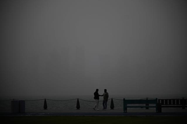 Men shake hands at the beach during a dust storm in Qatar's capital Doha, on January 25, 2026. (Photo by Mahmud HAMS / AFP)