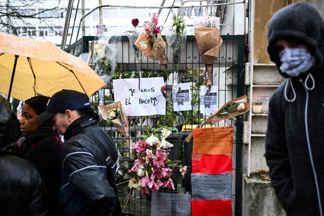 Protesters walk past a fence with flowers bouquets and messages in tribute to 35-year-old El Hacen Diarra, who died in police custody at the police station of Paris's 20th arrondissement, during a march in Paris on January 25, 2026. (Photo by Blanca CRUZ / AFP)