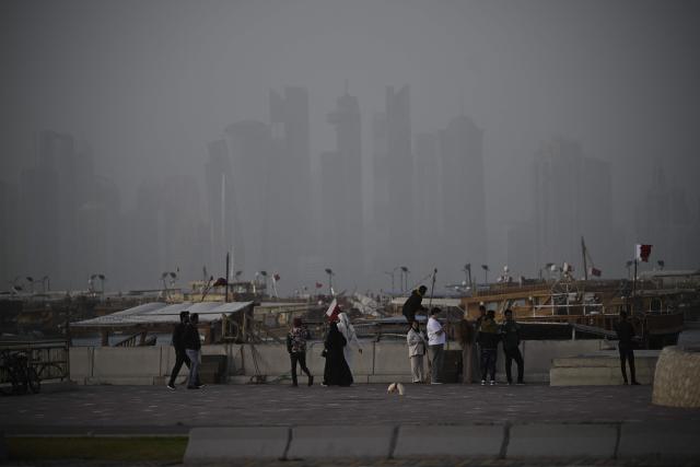 People stand near boats during a dust storm in Qatar's capital Doha, on January 25, 2026. (Photo by Mahmud HAMS / AFP)