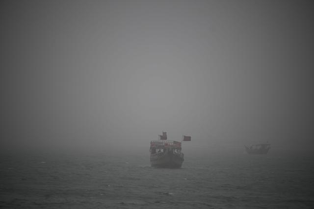 A photo taken on January 25, 2026 shows boats in the sea during a dust storm Qatar's capital Doha. (Photo by Mahmud HAMS / AFP)
