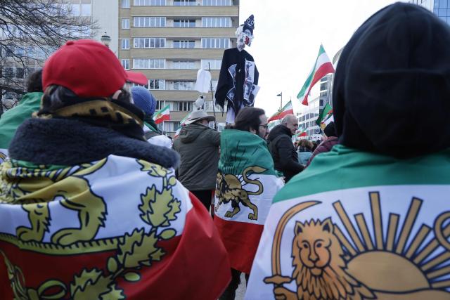 Protesters drapped in Iran flags with the Lion and Sun emblem attend a demonstration held by the Iranian diaspora in solidarity with protests currently taking place in Iran, at the European quarters of Brussels on January 25, 2026. Triggered on December 28, by protests over economic hardship, nationwide rallies in Iran surged on January 8, challenging the Islamic republic in power since 1979, before a violent crackdown that rights groups say has left thousands dead. (Photo by NICOLAS MAETERLINCK / Belga / AFP) / Belgium OUT