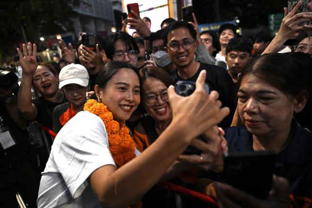 People’s Party MP Rukchanok Srinork takes photographs with supporters at a campaign rally ahead of the general election, in Bangkok on January 25, 2026. (Photo by Lillian SUWANRUMPHA / AFP)