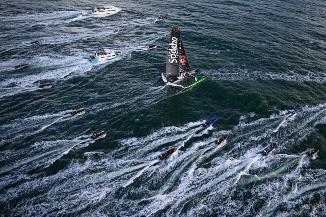 French skipper Thomas Coville and his crew members sail aboard the Ultim class multihull "Sodebo Ultim 3" after crossing the finish line at the end of their Jules Verne Trophy attempt, in the Atlantic Ocean, off the coast of Brest, Brittany, western France, on January 25, 2026. The Jules Verne Trophy is a prize for the fastest crewed, unassisted and non-stop circumnavigation of the world on any type of yacht. (Photo by Loic VENANCE / AFP)