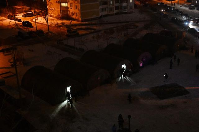People enter heated tents providing overnight accommodation for local residents whose apartments remain without heating due to recent Russian strikes damaging energy infrastructure in Kyiv on January 25, 2026, amid the Russian invasion of Ukraine. (Photo by Sergei GAPON / AFP)