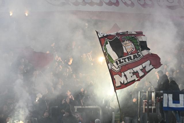 Metz supporters light flares as they cheer their team on from the stands at the start of the French L1 football match between Metz and Olympique Lyonnais (OL) at the Stade Saint-Symphorien in Longeville-les-Metz, eastern France, on January 25, 2026. (Photo by Jean-Christophe VERHAEGEN / AFP)