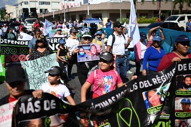 Activists hold allusive signs during a protest against President Nayib Bukele's policies -including the state of emergency, within the anti-gang crackdown, in force since March 2022 and which allows arrests without a warrant- in San Salvador, on January 25, 2026. (Photo by Marvin RECINOS / AFP)