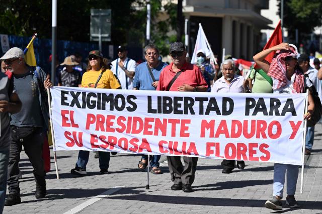 Activists hold a banner demanding the release of Venezuelan deposed President Nicolas Maduro and his wife Cilia Flores during a protest against President Nayib Bukele's policies -including the state of emergency, within the anti-gang crackdown, in force since March 2022 and which allows arrests without a warrant- in San Salvador, on January 25, 2026. (Photo by Marvin RECINOS / AFP)