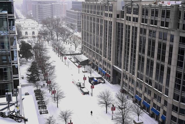 Snow falls as a person walks through downtown Washington, DC, on January 25, 2026. A massive winter storm on January 24 dumped snow and freezing rain from New Mexico to North Carolina as it swept across the United States towards the northeast, threatening tens of millions of Americans with blackouts, transportation chaos and bone-chilling cold. After battering the country's southwest and central areas, the storm system began to hit the heavily populated mid-Atlantic and northeastern states as a frigid air mass settled in across the nation. (Photo by Alex WROBLEWSKI / AFP)