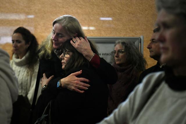 Two women hug each other as they attend a vigil in honour of the victims of the January 18 high-speed train accident that killed 45 people in Adamuz, on January 25, 2026, at the railway station of Huelva. One week after the train disaster involving two trains in southern Spain, which left 45 dead, remembrance ceremonies took place today in Huelva, where most of the victims came from, and in the town of Adamuz, where the collision occurred. (Photo by CRISTINA QUICLER / AFP)