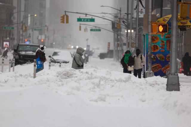 People cross Sixth Avenue in the snow in New York on January 25, 2026. A massive winter storm on January 24 dumped snow and freezing rain from New Mexico to North Carolina as it swept across the United States towards the northeast, threatening tens of millions of Americans with blackouts, transportation chaos and bone-chilling cold. After battering the country's southwest and central areas, the storm system began to hit the heavily populated mid-Atlantic and northeastern states as a frigid air mass settled in across the nation. (Photo by CHARLY TRIBALLEAU / AFP)