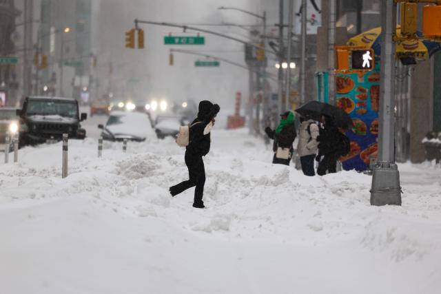 People cross Sixth Avenue in the snow in New York on January 25, 2026. A massive winter storm on January 24 dumped snow and freezing rain from New Mexico to North Carolina as it swept across the United States towards the northeast, threatening tens of millions of Americans with blackouts, transportation chaos and bone-chilling cold. After battering the country's southwest and central areas, the storm system began to hit the heavily populated mid-Atlantic and northeastern states as a frigid air mass settled in across the nation. (Photo by CHARLY TRIBALLEAU / AFP)