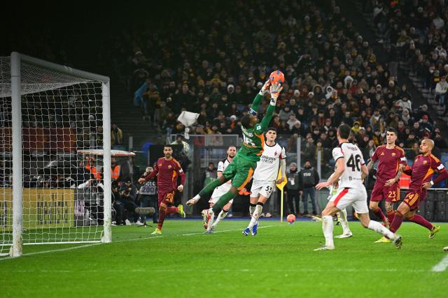 AC Milan's French goalkeeper #16 Mike Maignan (C) stretches to save the ball during the Italian Serie A football match between AS Roma and AC Milan at the Olympic Stadium in Rome on January 25, 2026. (Photo by Andreas SOLARO / AFP)