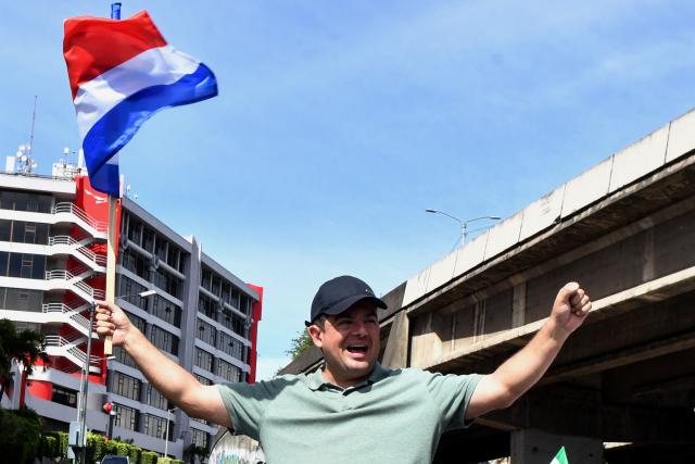 Costa Rica's presidential candidate of the Liberation party, Alvaro Ramos, gestures as he holds a national flag during his closing campaign rally in San Jose on January 25, 2026. Right-wing politician Laura Fernandez appears set to win Costa Rica's presidential election in the first round, according to two opinion polls published on January 21. (Photo by EZEQUIEL BECERRA / AFP)