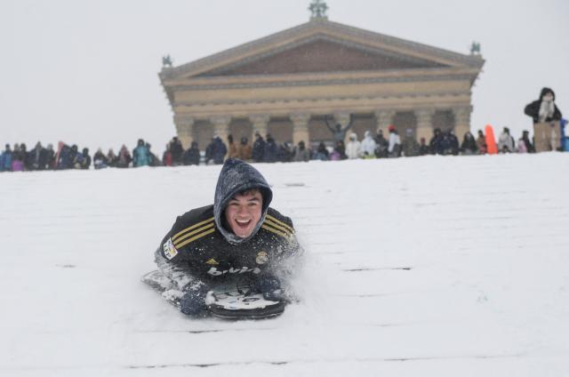 Philadelphia residents gather and sled down the steps of the Philadelphia Art Museum during a heavy snowfall in Philadelphia, Pennsylvania, on January 25, 2026. A massive winter storm headed towards the northeast United States after sweeping across much of the country, threatening tens of millions of Americans with blackouts, transportation chaos and bone-chilling cold. After battering the country's southwest and central areas, the storm system began to hit the heavily populated mid-Atlantic and northeastern states with snow and freezing rain as a frigid air mass settled in across the nation. (Photo by Matthew HATCHER / AFP)