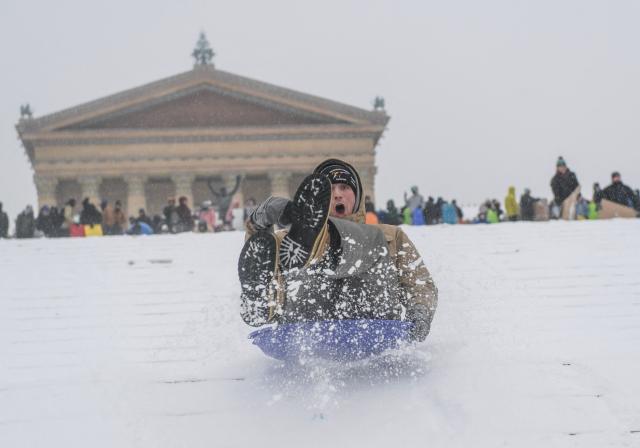 Philadelphia residents gather and sled down the steps of the Philadelphia Art Museum during a heavy snowfall in Philadelphia, Pennsylvania, on January 25, 2026. A massive winter storm headed towards the northeast United States after sweeping across much of the country, threatening tens of millions of Americans with blackouts, transportation chaos and bone-chilling cold. After battering the country's southwest and central areas, the storm system began to hit the heavily populated mid-Atlantic and northeastern states with snow and freezing rain as a frigid air mass settled in across the nation. (Photo by Matthew HATCHER / AFP)