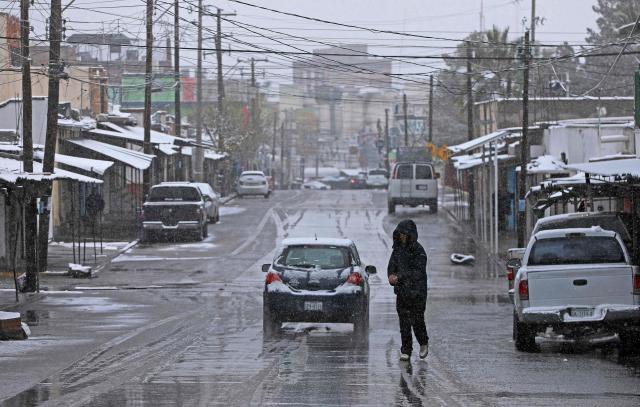 A person crosses a snow-covered street in Ciudad Juarez, Chihuahua State, Mexico on January 25, 2026. (Photo by Herika MARTINEZ / AFP)