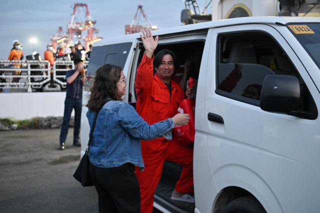 A Filipino crew member of the Singapore-flagged M/V Devon Bay waves after disembarking from Philippine coast guard ship BRP Teresa Magbanua after arriving at the international port in Manila on January 26, 2026, after they were turned over by the Chinese coast guard who rescued them near Scarborough Shoal in the disputed South China Sea. Chinese coast guard ships pulled 17 Filipino sailors, including two dead, from disputed waters in the South China Sea on January 24 after a cargo vessel capsized, China's military said. (Photo by Ted ALJIBE / AFP)