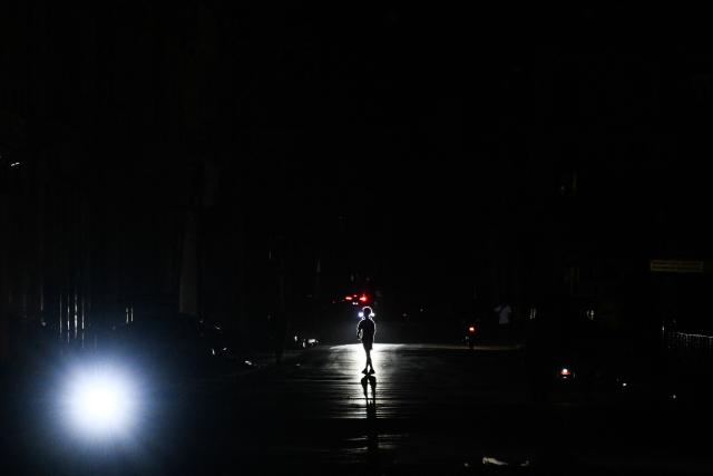 A kid crosses a street during a blackout in Havana on January 25, 2026. (Photo by YAMIL LAGE / AFP)