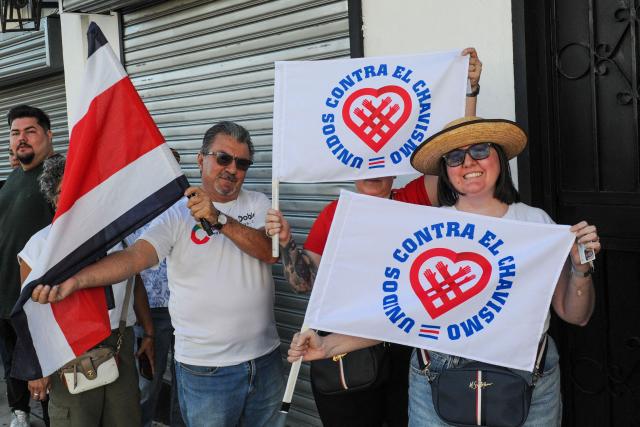 Supporters of Costa Rica's presidential candidate of the Citizen Agenda Coalition and former first lady, Claudia Dobles, show flags that reads in Spanish "United against Chavismo" during her closing campaign rally at the Mercadito La California in San Jose on January 25, 2026. Right-wing politician Laura Fernandez appears set to win Costa Rica's presidential election in the first round, according to two opinion polls published on January 21. (Photo by Marvin CARAVACA / AFP)