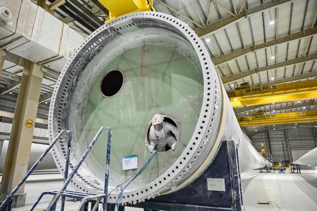 This photograph taken on November 5, 2025 shows an employee in personal protective equipment (PPE) suit working on a wind turbine blade at an Adani Group factory in Gujarat's port city of Mundra. The race for green energy is on. India, driven by soaring electricity demand and a push to reduce reliance on China, is rapidly producing solar panels, fuelling a booming yet uncertain market. (Photo by Shammi MEHRA / AFP) / TO GO WITH India-environment-politics-energy, FOCUS by Philippe Alfroy