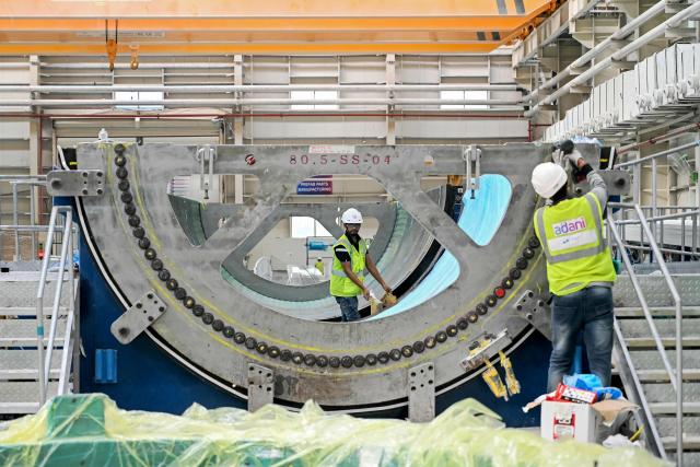 This photograph taken on November 5, 2025 shows employees working on a wind turbine blade at an Adani Group factory in Gujarat's port city of Mundra. The race for green energy is on. India, driven by soaring electricity demand and a push to reduce reliance on China, is rapidly producing solar panels, fuelling a booming yet uncertain market. (Photo by Shammi MEHRA / AFP) / TO GO WITH India-environment-politics-energy, FOCUS by Philippe Alfroy