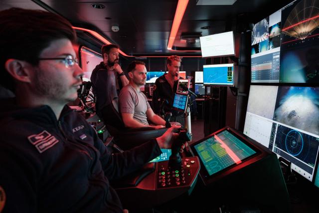 This photo taken on January 10, 2026 shows the crew of the OceanXplorer, a research vessel operated by the marine non-profit OceanX, operating a remotely operated vehicle (ROV) in a control room while marine scientists monitor deep-sea feeds in the waters off Sulawesi island. A dome-fronted submersible sinks beneath the waves off Indonesia, heading nearly 1,000 metres down to the realm of purple-frilled corals and bioluminescent shrimp. This month, AFP boarded one of two submersibles belonging to OceanX, a non-profit founded by billionaire Ray Dalio and his son that works with scientists on its OceanXplorer ship to study the marine world. (Photo by YASUYOSHI CHIBA / AFP) / To go with 'INDONESIA-OCEANX-OCEANS-ENVIRONMENT-RESEARCH-SCIENCE' by Sara HUSSEIN