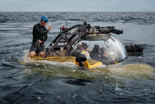 TOPSHOT - This photo taken on January 12, 2026 shows the crew of the OceanXplorer, a research vessel operated by the marine non-profit OceanX, coordinating safety protocols with a submersible pilot before a deep-sea operations in the waters off Sulawesi island. A dome-fronted submersible sinks beneath the waves off Indonesia, heading nearly 1,000 metres down to the realm of purple-frilled corals and bioluminescent shrimp. This month, AFP boarded one of two submersibles belonging to OceanX, a non-profit founded by billionaire Ray Dalio and his son that works with scientists on its OceanXplorer ship to study the marine world. (Photo by YASUYOSHI CHIBA / AFP) / To go with 'INDONESIA-OCEANX-OCEANS-ENVIRONMENT-RESEARCH-SCIENCE' by Sara HUSSEIN
