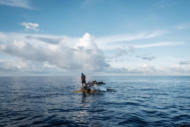 This photo taken on January 9, 2026 shows the crew of the OceanXplorer, a research vessel operated by the marine non-profit OceanX, standing atop a surfaced submersible to attach a recovery line for winching, in the waters off Sulawesi island. A dome-fronted submersible sinks beneath the waves off Indonesia, heading nearly 1,000 metres down to the realm of purple-frilled corals and bioluminescent shrimp. This month, AFP boarded one of two submersibles belonging to OceanX, a non-profit founded by billionaire Ray Dalio and his son that works with scientists on its OceanXplorer ship to study the marine world. (Photo by YASUYOSHI CHIBA / AFP) / To go with 'INDONESIA-OCEANX-OCEANS-ENVIRONMENT-RESEARCH-SCIENCE' by Sara HUSSEIN