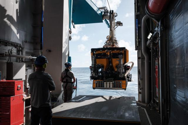This photo taken on January 10, 2026 shows a remotely operated vehicle (ROV) being deployed into the sea from the OceanXplorer, a research vessel operated by the marine non-profit OceanX, for a deep-sea mission in the waters off Sulawesi island. A dome-fronted submersible sinks beneath the waves off Indonesia, heading nearly 1,000 metres down to the realm of purple-frilled corals and bioluminescent shrimp. This month, AFP boarded one of two submersibles belonging to OceanX, a non-profit founded by billionaire Ray Dalio and his son that works with scientists on its OceanXplorer ship to study the marine world. (Photo by YASUYOSHI CHIBA / AFP) / To go with 'INDONESIA-OCEANX-OCEANS-ENVIRONMENT-RESEARCH-SCIENCE' by Sara HUSSEIN