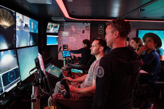 This photo taken on January 10, 2026 shows the crew of the OceanXplorer, a research vessel operated by the marine non-profit OceanX, operating a remotely operated vehicle (ROV) in a control room while marine scientists monitor deep-sea feeds in the waters off Sulawesi island. A dome-fronted submersible sinks beneath the waves off Indonesia, heading nearly 1,000 metres down to the realm of purple-frilled corals and bioluminescent shrimp. This month, AFP boarded one of two submersibles belonging to OceanX, a non-profit founded by billionaire Ray Dalio and his son that works with scientists on its OceanXplorer ship to study the marine world. (Photo by YASUYOSHI CHIBA / AFP) / To go with 'INDONESIA-OCEANX-OCEANS-ENVIRONMENT-RESEARCH-SCIENCE' by Sara HUSSEIN