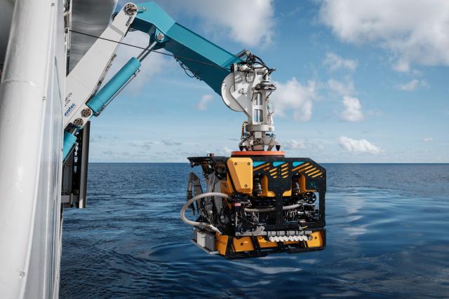 This photo taken on January 10, 2026 shows a remotely operated vehicle (ROV) being deployed into the sea from the OceanXplorer, a research vessel operated by the marine non-profit OceanX, for a deep-sea mission in the waters off Sulawesi island. A dome-fronted submersible sinks beneath the waves off Indonesia, heading nearly 1,000 metres down to the realm of purple-frilled corals and bioluminescent shrimp. This month, AFP boarded one of two submersibles belonging to OceanX, a non-profit founded by billionaire Ray Dalio and his son that works with scientists on its OceanXplorer ship to study the marine world. (Photo by YASUYOSHI CHIBA / AFP) / To go with 'INDONESIA-OCEANX-OCEANS-ENVIRONMENT-RESEARCH-SCIENCE' by Sara HUSSEIN