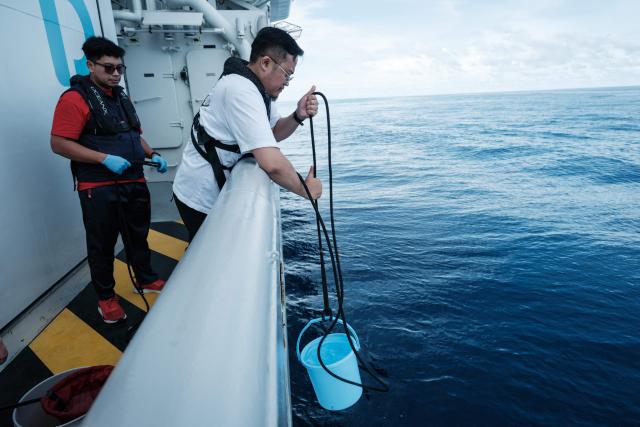 This photo taken on January 9, 2026, shows Indonesian scientists collecting seawater samples to examine plankton in the ocean on the OceanXplorer, a research vessel operated by the marine non-profit OceanX, in waters off Sulawesi island. A dome-fronted submersible sinks beneath the waves off Indonesia, heading nearly 1,000 metres down to the realm of purple-frilled corals and bioluminescent shrimp. This month, AFP boarded one of two submersibles belonging to OceanX, a non-profit founded by billionaire Ray Dalio and his son that works with scientists on its OceanXplorer ship to study the marine world. (Photo by YASUYOSHI CHIBA / AFP) / To go with: INDONESIA-OCEANX-OCEANS-ENVIRONMENT-RESEARCH-SCIENCE, by Sara HUSSEIN