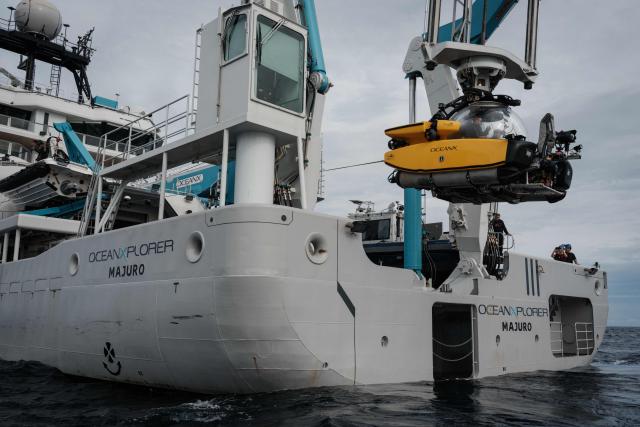 This photo taken on January 12, 2026, shows a submersible being lowered by crane from the OceanXplorer, a research vessel operated by the marine non-profit OceanX, for a deep-sea mission in the waters off Sulawesi island. A dome-fronted submersible sinks beneath the waves off Indonesia, heading nearly 1,000 metres down to the realm of purple-frilled corals and bioluminescent shrimp. This month, AFP boarded one of two submersibles belonging to OceanX, a non-profit founded by billionaire Ray Dalio and his son that works with scientists on its OceanXplorer ship to study the marine world. (Photo by YASUYOSHI CHIBA / AFP) / To go with: INDONESIA-OCEANX-OCEANS-ENVIRONMENT-RESEARCH-SCIENCE, by Sara HUSSEIN