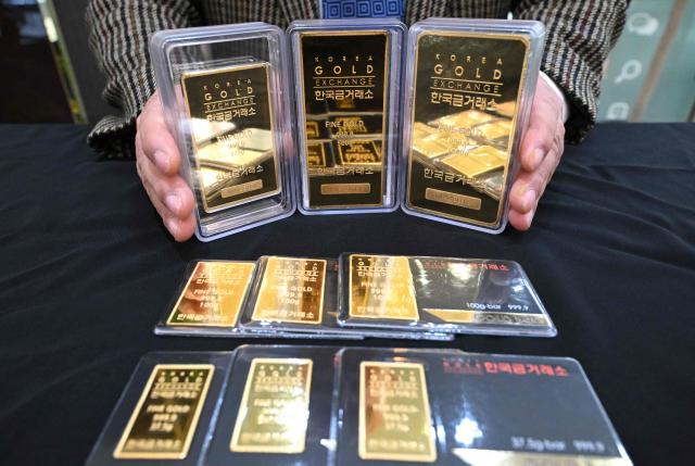 An employee displays gold bars at a store of the Korea Gold Exchange in Seoul on January 26, 2026. The price of safe-haven asset gold surpassed $5,000 on January 25, hitting a record amid rising global uncertainty and turmoil set off by US President Donald Trump's policies. (Photo by Jung Yeon-je / AFP)