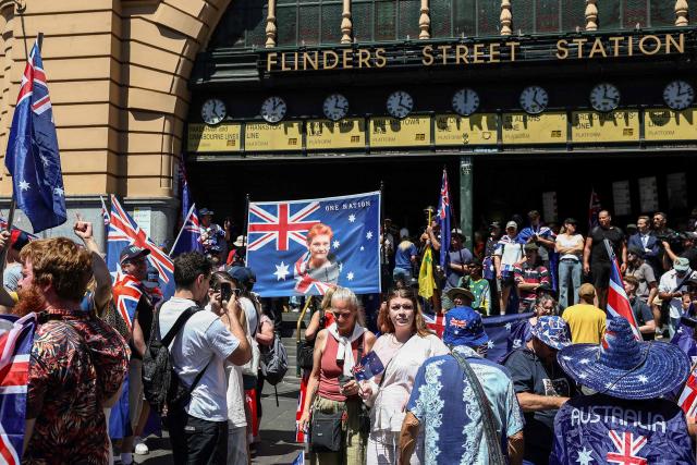 A demonstrator displays a banner showing One Nation Senator Pauline Hanson (C) during an anti-government protest rally on Australia Day in Melbourne on January 26, 2026. (Photo by Izhar KHAN / AFP)