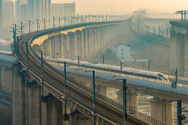 A high speed train runs on elevated tracks in Nanjing, in China’s eastern Jiangsu province on January 25, 2026. China will introduce a new national train schedule from January 26, with 12,130 scheduled passenger trains and 23,748 freight trains operating across the country, including high speed trains. (Photo by AFP) / China OUT