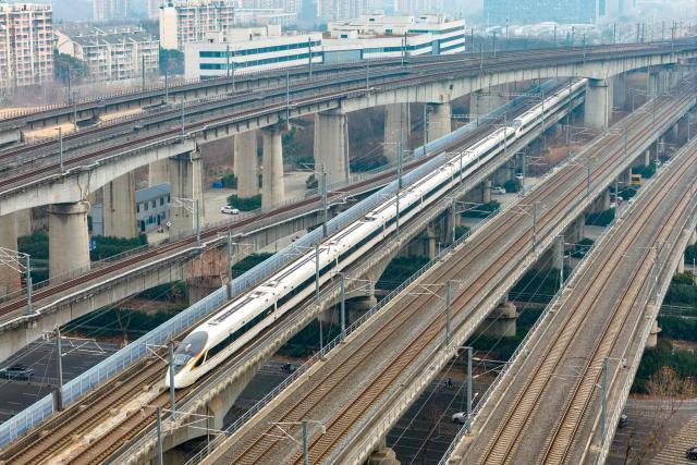 A high speed train runs on elevated tracks in Nanjing, in China’s eastern Jiangsu province on January 25, 2026. China will introduce a new national train schedule from January 26, with 12,130 scheduled passenger trains and 23,748 freight trains operating across the country, including high speed trains. (Photo by AFP) / China OUT