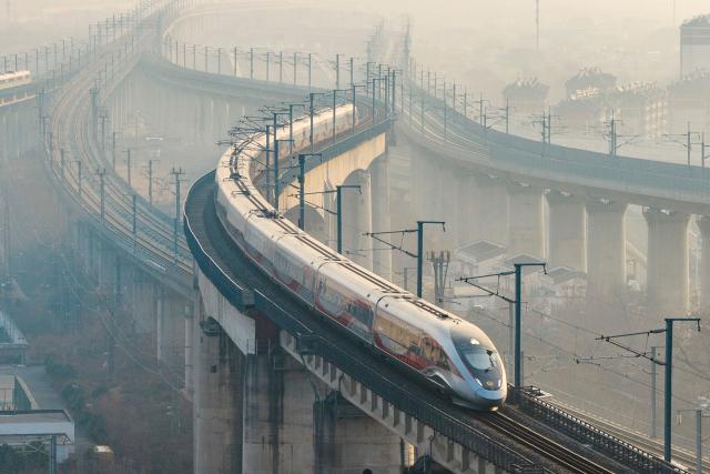 A high speed train runs on elevated tracks in Nanjing, in China’s eastern Jiangsu province on January 25, 2026. China will introduce a new national train schedule from January 26, with 12,130 scheduled passenger trains and 23,748 freight trains operating across the country, including high speed trains. (Photo by AFP) / China OUT