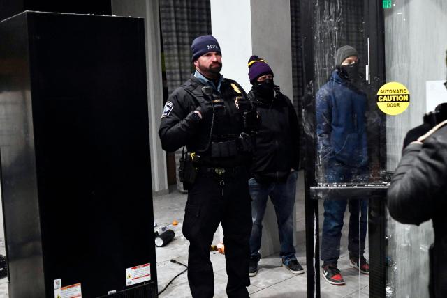 A Minneapolis Police Officer (L) stands guard as protesters participate in the "ICE OUT! Noise Demo" at the entrance of a hotel in Minneapolis, Minnesota on January 25, 2026. On January 24, federal agents shot dead US citizen Alex Pretti, a 37-year-old ICU nurse, while scuffling with him on an icy roadway, less than three weeks after an immigration officer shot and killed Renee Good, also 37, in her car.
His killing sparked new protests and impassioned demands by local leaders for the Trump administration to end its operation in the city. (Photo by Octavio JONES / AFP)