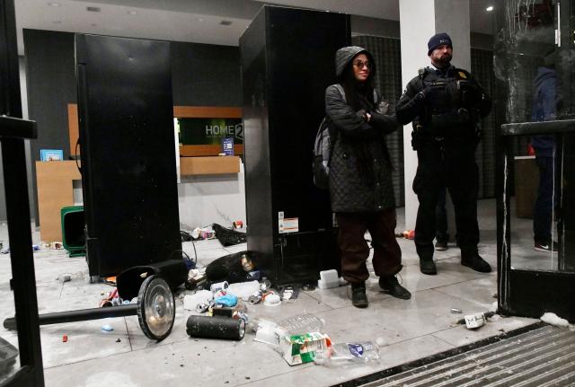 A Minneapolis Police Officer (R) stands guard after protesters threw trash at a hotel lobby during the "ICE OUT! Noise Demo" in Minneapolis, Minnesota on January 25, 2026. On January 24, federal agents shot dead US citizen Alex Pretti, a 37-year-old ICU nurse, while scuffling with him on an icy roadway, less than three weeks after an immigration officer shot and killed Renee Good, also 37, in her car.
His killing sparked new protests and impassioned demands by local leaders for the Trump administration to end its operation in the city. (Photo by Octavio JONES / AFP)