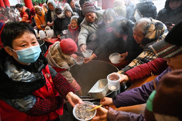 People dish out Laba congee, a porridge made with nuts and fruit, on the Laba festival, which marks the eighth day of the twelfth lunar month, and the beginning of the Chinese New Year buildup period, in Nanjing, in China’s eastern Jiangsu province on January 26, 2026. (Photo by AFP) / China OUT