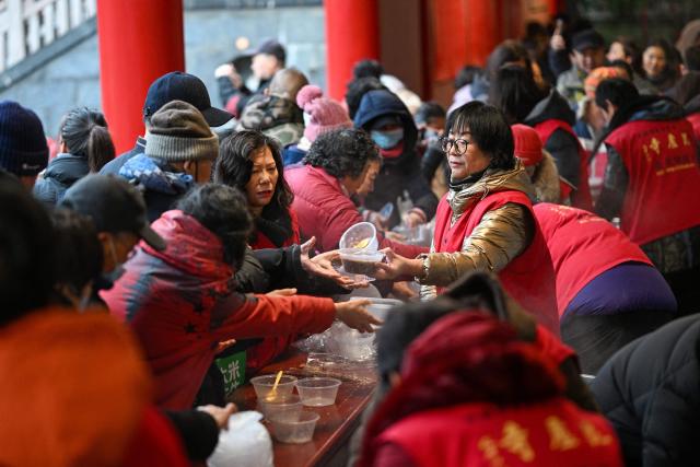People dish out Laba congee, a porridge made with nuts and fruit, on the Laba festival, which marks the eighth day of the twelfth lunar month, and the beginning of the Chinese New Year buildup period, in Nanjing, in China’s eastern Jiangsu province on January 26, 2026. (Photo by AFP) / China OUT