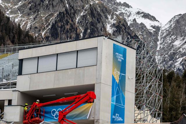 (FILES) Construction workers put up a banner with the Olympic rings on it at the Biathlon venue in Antholz, northern Italy, prior to the Milano Cortina 2026 Olympic Games, on January 23, 2026. (Photo by Odd ANDERSEN / AFP)