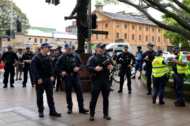 Police keep watch during the annual "Invasion Day" rally through the streets of Sydney on Australia Day on January 26, 2026. Tens of thousands of Australians protested over the treatment of Indigenous people as they rallied on a contentious national holiday that also marks the arrival of European colonists more than 200 years ago. (Photo by Steven Markham / AFP)
