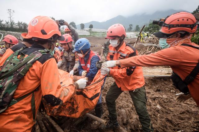 Rescuers recover the body of a victim buried by a landslide in Pasirlangu village, Bandung, West Java, on January 26, 2026. The death toll in a massive Indonesian landslide hit 17 on January 26 as rescuers used heavy equipment to hunt for dozens still missing days after heavy rains unleashed a torrent of mud. (Photo by Timur Matahari / AFP)